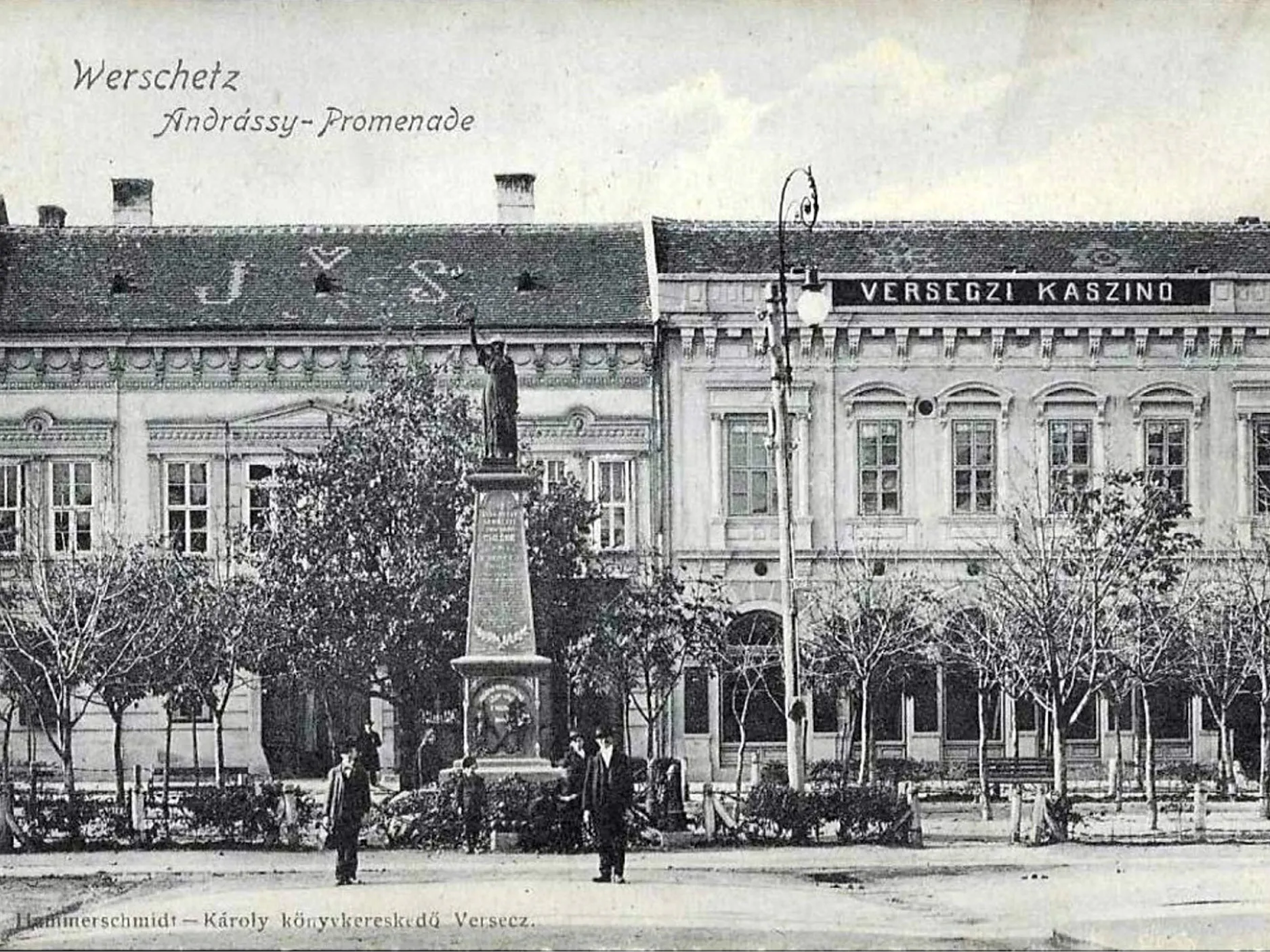 Stara razglednica. Trg s spomenikom, v ozadju pročelje stavb. Na enem od njih je napis Kazino. Črnobela reprodukcija.